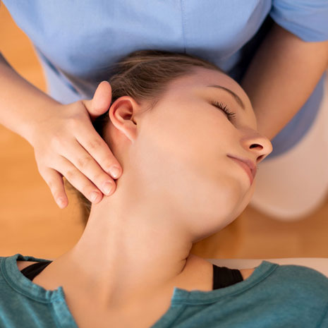 chiropractor adjust a female patient’s neck